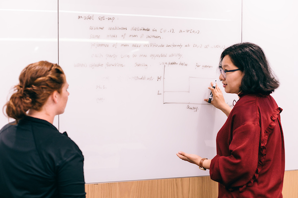 Two PhD students working at a whiteboard